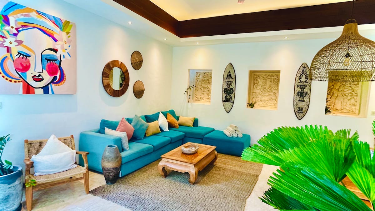 The cozy seating area in the living room invites relaxation with its vibrant teal sofa and colorful cushions.
